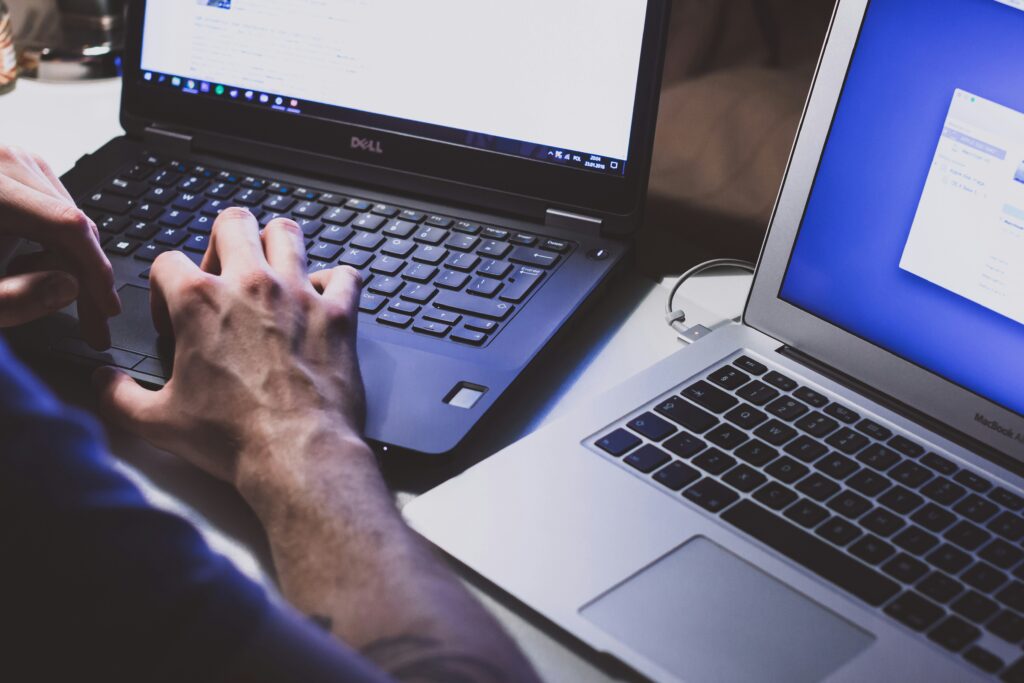 Image from above of someone on a laptop with another open, representing Kazzicoms team